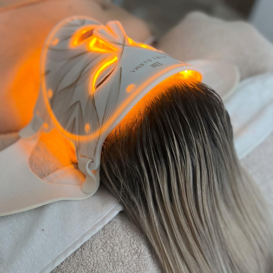 Pure Derma LED face mask glowing yellow on a client lying on a treatment bed