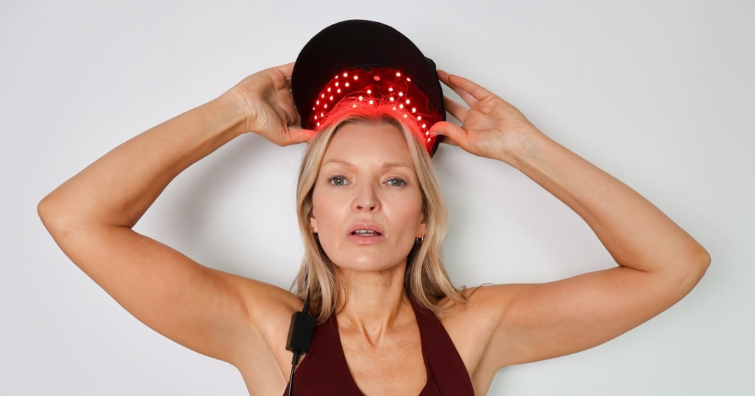 Woman wearing the Pure Derma LED Hair Growth Cap with red LED light therapy glowing on her scalp, against a plain white background