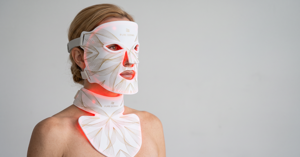 Woman wearing the LED Light Therapy Face, Neck and Decolletage Mask with red LED light glowing.