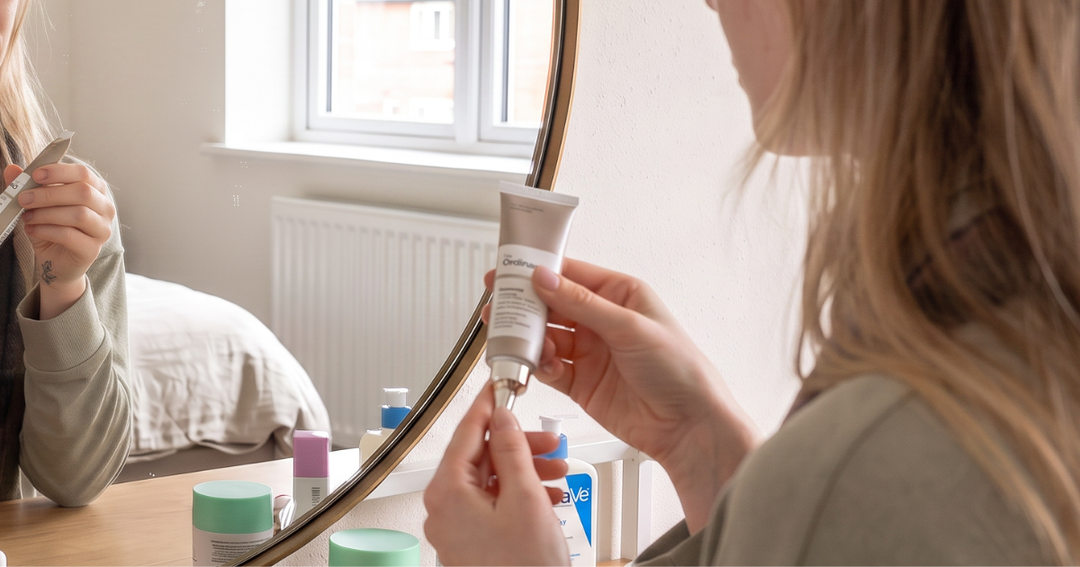 Woman applying retinol serum as part of her evening skincare routine at a mirror