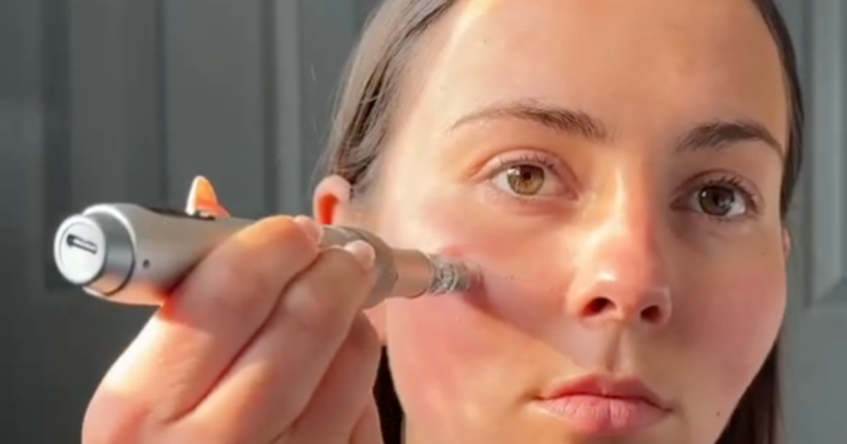 Woman using a microneedling pen device under her eye during an at-home autumn skincare routine