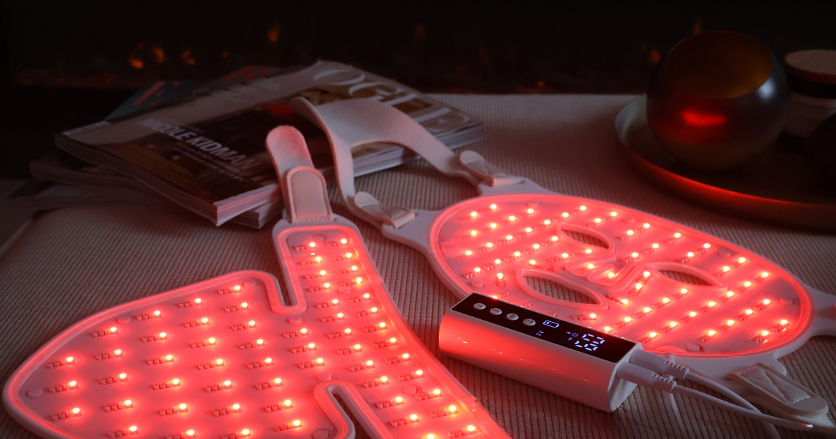 Pure Derma LED Light Therapy Face, Neck & Decolletage Mask glowing red in a cosy evening skincare setting