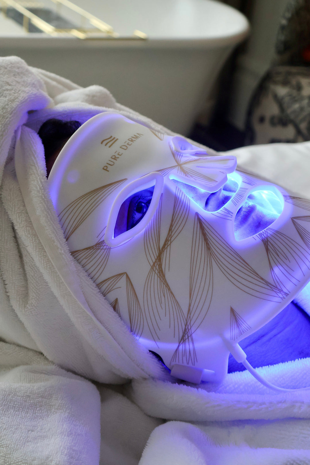 Close-up of a woman wearing an LED face mask lit up in blue LED light