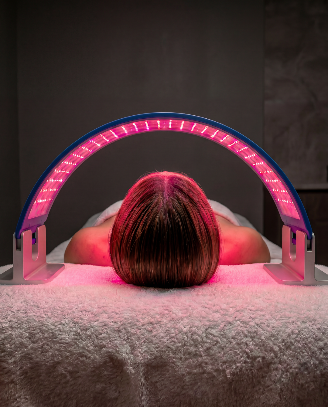 Close up of a woman using a light therapy device on her face