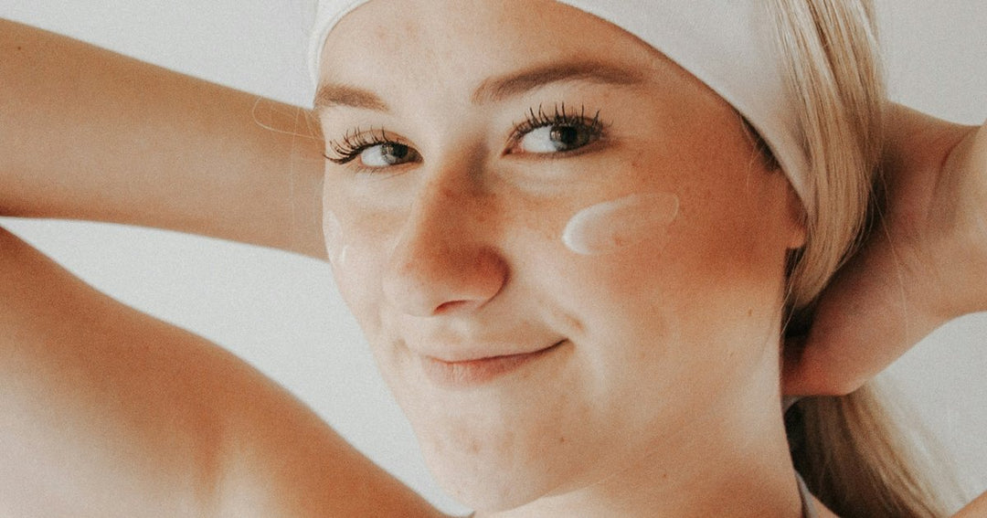 Woman applying moisturiser to her face as part of her summer skin recovery routine