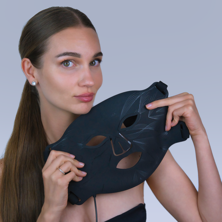 female model holding black LED light therapy face mask